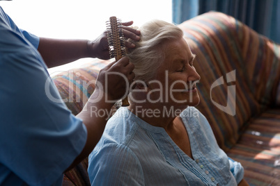 Midsection of doctor combing hair of female patient