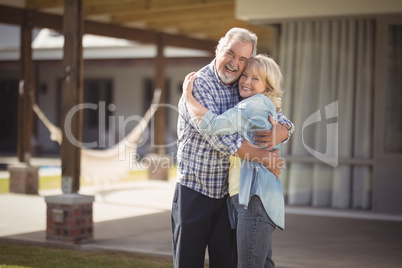 Senior couple embracing while standing outside their house