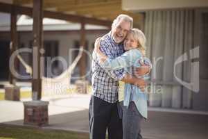 Senior couple embracing while standing outside their house