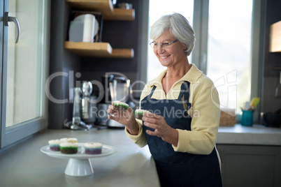 Senior woman picking up the cupcake from the tray