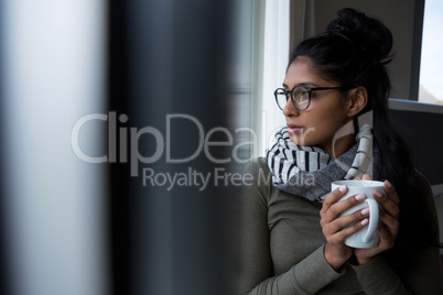 Young woman with coffee cup by window