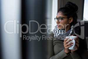 Young woman with coffee cup by window