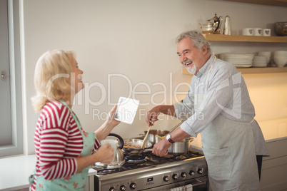 Senior couple interacting while preparing food