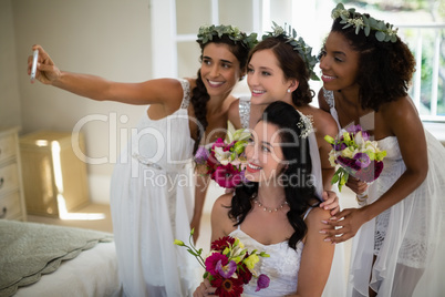Bride and bridesmaid taking selfie at home