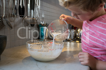 Boy pouring milk in batter