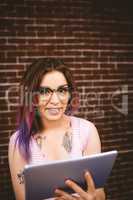 Smiling woman using digital tablet against brick wall