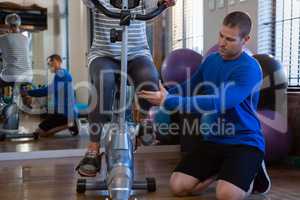 Physiotherapist assisting senior woman in performing exercise on exercise bike