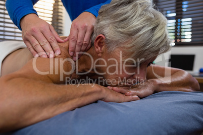 Physiotherapist giving shoulder massage to a senior woman