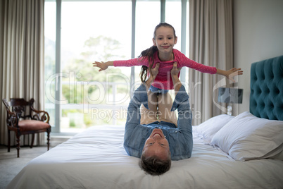 Smiling father lifting her daughter on the bed