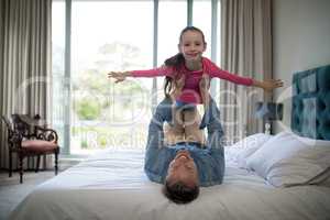 Smiling father lifting her daughter on the bed