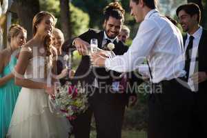 Groom pouring champagne into his friends glasses