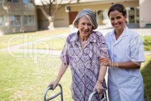 Portrait of doctor helping senior woman in walking