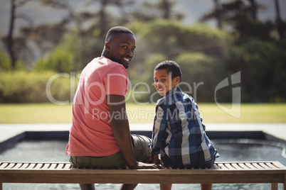 Smiling father and son sitting together on bench