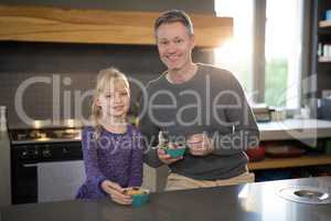 Little girl and father posing while eating fruits from a bowl