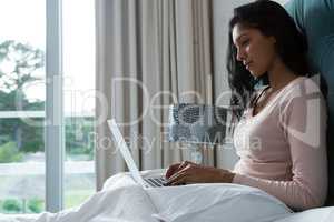Young woman using laptop on bed
