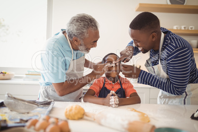 Multi-generation family with flour on the nose standing in the kitchen