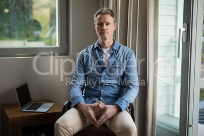 Confident man sitting on chair in living room