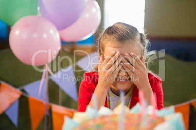 Cute girl covering her eyes during birthday party