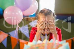 Cute girl covering her eyes during birthday party