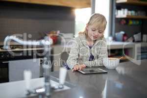 Little girl using tablet while eating cereals from a bowl