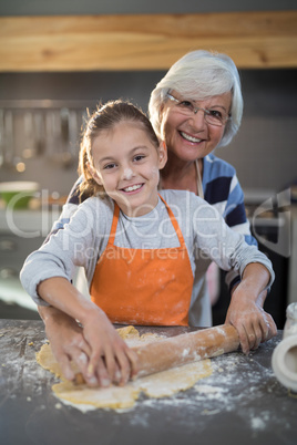 Grandmother and granddaughter posing while flattening dough