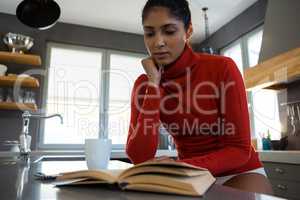 Woman reading book in kitchen