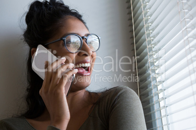 Happy woman talking on phone by window