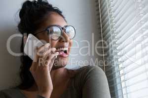 Happy woman talking on phone by window