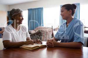 Nurse talking to senior woman while sitting at table
