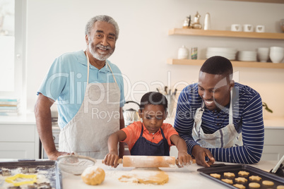 Boy preparing cookie dough with his father and grandfather in kitchen