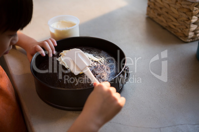 Cropped image of girl spreading cream on cake