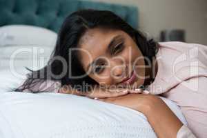 Thoughtful woman resting on bed