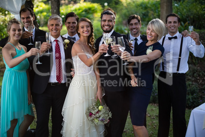 Newly married couple and guests holding glasses of champagne