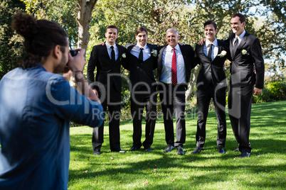 Photographer taking photo of groom and groomsmen