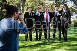 Photographer taking photo of groom and groomsmen