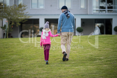 Father and daughter holding hands and walking in the garden