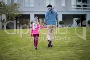 Father and daughter holding hands and walking in the garden