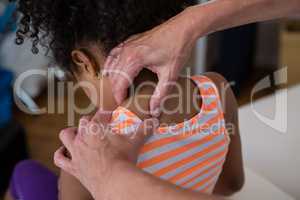 Physiotherapist giving neck massage to girl patient