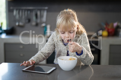 Little girl eating cereals rings with spoon from a bowl