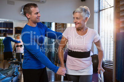 Man helping senior woman to walk with walker
