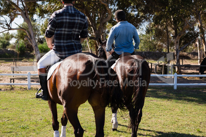 Two male friends riding horse in the ranch