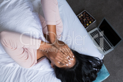 Woman covering face on bed
