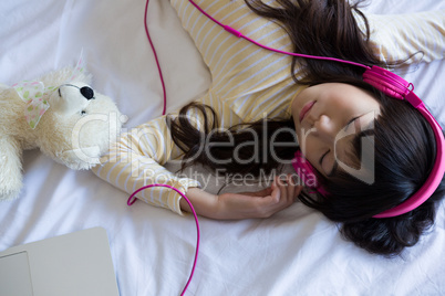 Girl listening to music while sleeping on bed