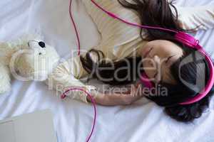Girl listening to music while sleeping on bed