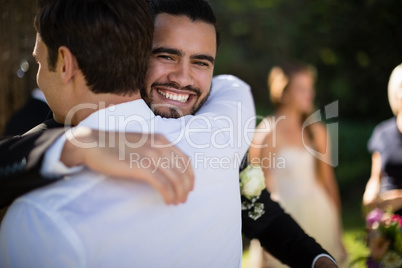 Groom embracing waiter in park