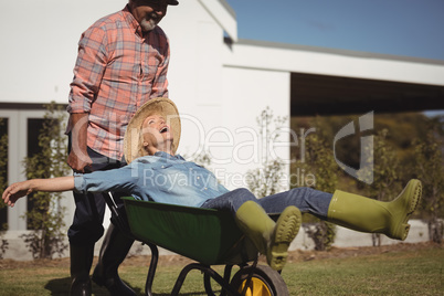 Smiling senior man giving woman ride in wheelbarrow