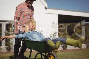 Smiling senior man giving woman ride in wheelbarrow