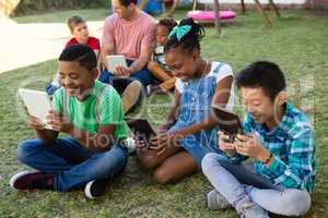 Children using tablet computer with man at park