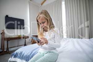 Girl using mobile phone on bed in bedroom