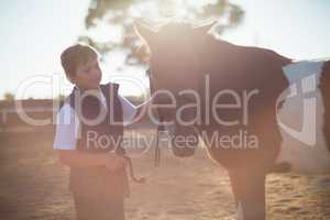 Boy holding the reins of a horse in the ranch